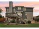 Two-story house with a deck and dining set, staircase, and lush green landscaping at sunset at 2851 Weatherstone Se Cir, Conyers, GA 30094