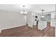 Open dining area with wood-look floors and modern chandelier, and views of renovated kitchen at 4477 Timber Ridge Dr, Douglasville, GA 30135