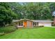 Charming ranch-style home with well-manicured lawn, mature trees, and an inviting orange front door at 2072 Castleway Ne Dr, Atlanta, GA 30345