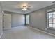 Neutral bedroom featuring plush carpet, two windows providing lots of light, and a ceiling fan at 4845 Dartford Dr, Powder Springs, GA 30127