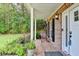 Inviting front porch with brick flooring and a rocking chair, surrounded by lush landscaping at 4845 Dartford Dr, Powder Springs, GA 30127