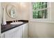 Bright bathroom features a classic vanity with a sink, elegant mirror, and a large window overlooking lush greenery at 508 Hastings Dr, Peachtree City, GA 30269