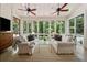 Sunroom featuring plentiful natural light with comfortable white seating, hardwood floors, and multiple ceiling fans at 508 Hastings Dr, Peachtree City, GA 30269