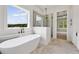 Spa-like bathroom with soaking tub, glass enclosed shower, marble floors, and a large window offering views at 158 Palisade Dr, Rydal, GA 30171
