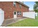 Brick home exterior with a patio and grassy backyard area, enclosed with a white and green fence at 215 Morris Ln, Woodstock, GA 30188