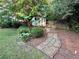 Landscaped backyard featuring a stone path and shed surrounded by lush plants and greenery at 2610 Stokesley Way, Snellville, GA 30078