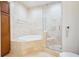 Bright bathroom featuring a soaking tub, glass enclosed shower, and tiled walls at 2828 Peachtree Nw Rd # 2002, Atlanta, GA 30305