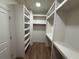 Walk-in closet with custom shelving, storage, and hardwood floors at 4110 Post Gate Ct, Cumming, GA 30040