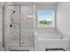Bathroom features a glass shower, garden tub, and marble tiling with a view to the exterior at 3860 Oxford Park Ln, Cumming, GA 30040