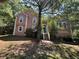 Exterior shot of a charming, light pink, stucco house surrounded by lush greenery and mature trees at 610 Coolsprings Ln, Woodstock, GA 30188