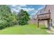 View of the spacious backyard that features mature trees and a home with a deck at 1727 Shire Village Dr, Sugar Hill, GA 30518