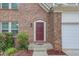 Close-up of the home's inviting entryway with a maroon front door, brick facade, and manicured landscaping at 1727 Shire Village Dr, Sugar Hill, GA 30518