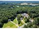 Aerial view showcases a large estate with wooded acreage, multiple structures, and a private pool at 5427 Highway 81, Loganville, GA 30052