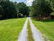 Long gravel driveway leading to the house in the distance, bordered by green grass and mature trees at 5427 Highway 81, Loganville, GA 30052