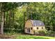 A charming outbuilding featuring painted wood siding, a gray roof, and set within a wooded lot at 5427 Highway 81, Loganville, GA 30052