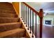 Carpeted staircase with dark wooden railings leading to the living area and fireplace at 5427 Highway 81, Loganville, GA 30052