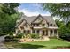 Elegant home featuring a manicured lawn, stone accents, and a welcoming covered porch at 930 Shepards Ct, Roswell, GA 30075