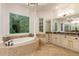 Lavish bathroom featuring and vanities, a soaking tub, and large windows with a backyard view at 930 Shepards Ct, Roswell, GA 30075