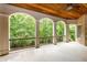 Covered outdoor patio with wood ceiling, brick pillars, and scenic wooded views at 930 Shepards Ct, Roswell, GA 30075