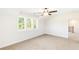 Bright bedroom with neutral carpet, white walls, ceiling fan, and large window overlooking lush greenery at 102 Red Oak Ln, Carrollton, GA 30116