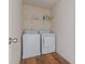 Functional laundry room with a washer, dryer, wooden floor, and shelf at 27 Autumn Canyon Se Path, Cartersville, GA 30121