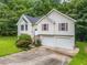 Two-story home with a lush green front lawn, a two-car garage, and surrounded by mature trees offering privacy at 87 Fair Havens Dr, Hiram, GA 30141