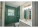 Stylishly renovated bathroom featuring green tiled shower, white vanity, quartz countertop, and modern fixtures at 2524 Glenrock Dr, Decatur, GA 30032