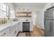 Bright kitchen featuring a farmhouse sink, white cabinets, quartz countertops, wood floating shelves, and stainless steel appliances at 995 Lena Nw St, Atlanta, GA 30314