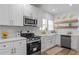 Modern kitchen featuring white cabinets, stainless steel appliances, farmhouse sink, and stylish wood floating shelves at 995 Lena Nw St, Atlanta, GA 30314