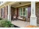 Cozy front porch with a bench, rocking chair, brick accents, and meticulously landscaped surroundings at 1626 Waterchase Dr, Dacula, GA 30019