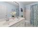 Light-filled bathroom featuring a dual sink vanity, patterned shower curtain, and modern finishes at 520 Weatherend Ct, Johns Creek, GA 30022