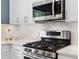 Close-up of updated kitchen featuring stainless steel stove, microwave, white cabinets, and marble countertops at 520 Weatherend Ct, Johns Creek, GA 30022