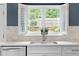 White open-shutter kitchen window overlooks the backyard greenery above the kitchen sink at 520 Weatherend Ct, Johns Creek, GA 30022