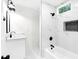 Modern bathroom featuring new fixtures, white marble tile, and black accents, with tub and shower at 630 Pennylake Ct, Stone Mountain, GA 30087