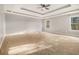 Large bedroom with a trey ceiling, carpeted floor, two windows, and neutral-colored walls at 7691 Brazos Trl, Fairburn, GA 30213