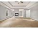 Spacious bedroom features a fireplace, tray ceiling, carpet, natural light, and ensuite bathroom entrance at 7691 Brazos Trl, Fairburn, GA 30213