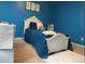 Bedroom with blue walls, carpeted floors, and bed frame with white faux fur rug on floor at 11547 Hathaway Dr, Hampton, GA 30228