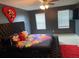 Unique bedroom showcasing a tufted platform bed with a vibrant floral comforter and a large heart decoration on the wall at 11547 Hathaway Dr, Hampton, GA 30228