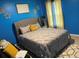 Comfortable bedroom with blue walls, grey headboard and comforter, and a decorative pillow at 11547 Hathaway Dr, Hampton, GA 30228