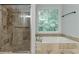 Bright bathroom featuring a soaking tub and separate glass-enclosed shower with tiled surround and trim at 1790 Abinger Ln, Lawrenceville, GA 30043
