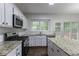 Bright kitchen boasts stainless appliances, granite counters, and a view to backyard at 1790 Abinger Ln, Lawrenceville, GA 30043