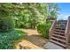 Landscaped backyard featuring mature trees and greenery, accessible via wooden steps from a deck at 3059 Brookgreen Trl, Lawrenceville, GA 30043