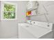 Bright laundry area with white washer, dryer, storage shelves, and natural light from the adjacent window at 3059 Brookgreen Trl, Lawrenceville, GA 30043