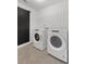 Well-lit laundry room features modern washer and dryer, contrasting black door, and stylish herringbone tile flooring at 4317 Azalea Ridge Way, Hoschton, GA 30548