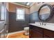 Half bathroom featuring dark wood cabinets, wainscoting, a modern mirror, and hardwood floors at 2680 Bay Ridge Dr, Loganville, GA 30052