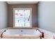 Close up of a soaking tub under a colorful stained glass window surrounded by tile at 2680 Bay Ridge Dr, Loganville, GA 30052