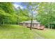 Back exterior of the home with an expansive wooden deck and a large lawn with mature trees at 3329 Walt Stephens Rd, Stockbridge, GA 30281