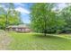 Back exterior of the home with an expansive wooden deck and a large lawn with mature trees at 3329 Walt Stephens Rd, Stockbridge, GA 30281