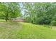 Back exterior of the home with an expansive wooden deck and a large lawn with mature trees at 3329 Walt Stephens Rd, Stockbridge, GA 30281