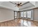 Primary bedroom with tray ceiling, fan, sliding barn door, and hardwood floors at 4770 Spring Park Cir, Suwanee, GA 30024